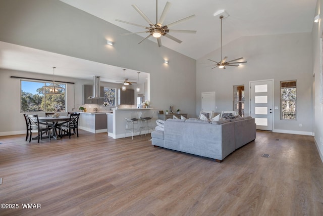 living room featuring high vaulted ceiling, light wood-style flooring, and baseboards