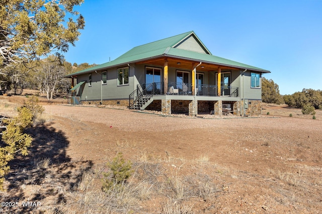 view of front of property with covered porch, metal roof, stairway, and central air condition unit