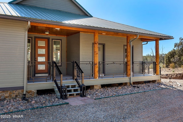 view of exterior entry with covered porch and metal roof