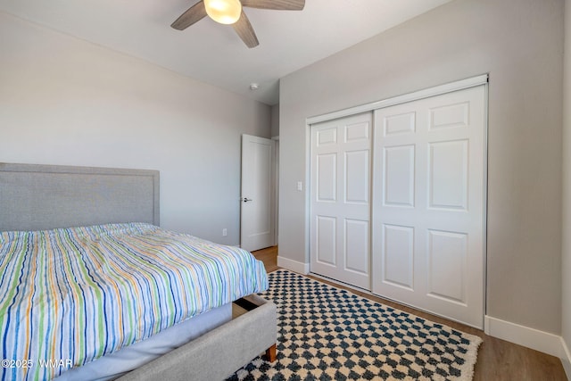 bedroom featuring ceiling fan, a closet, wood finished floors, and baseboards