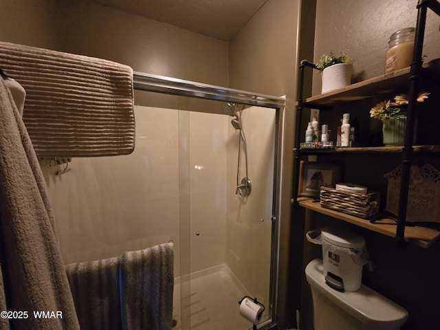 bathroom featuring toilet, a stall shower, and a textured wall