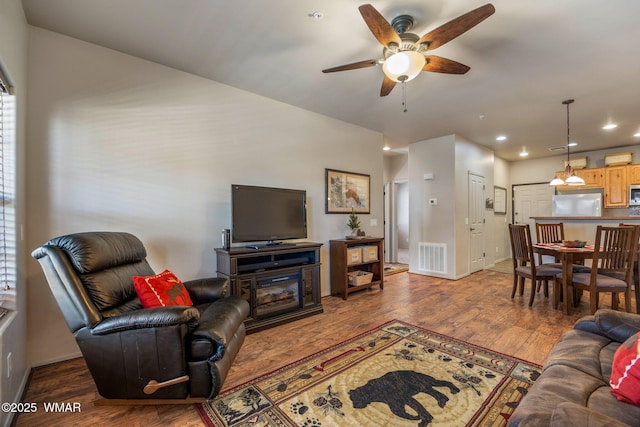 living area with visible vents, ceiling fan, wood finished floors, and baseboards
