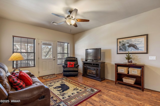 living room with wood finished floors, ceiling fan, and visible vents
