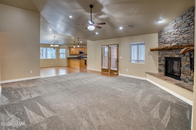 unfurnished living room featuring vaulted ceiling, a fireplace, visible vents, and light colored carpet