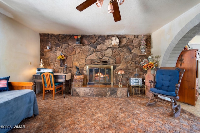 1051 Dusty Ln, Show Low, AZ 85901 - living room featuring ceiling fan, carpet floors, arched walkways, a fireplace, and a textured ceiling