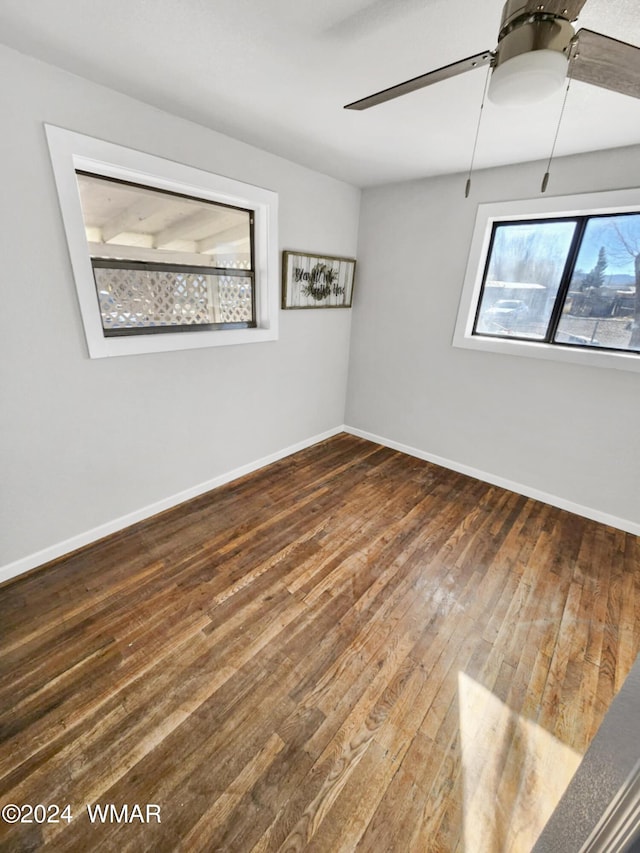 unfurnished room with ceiling fan, baseboards, and dark wood-style flooring