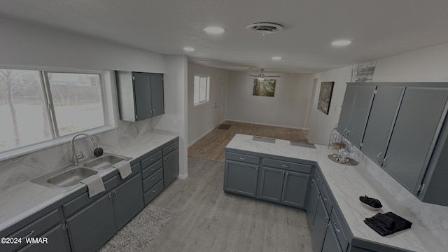 kitchen featuring light wood-style flooring, a sink, visible vents, and gray cabinetry