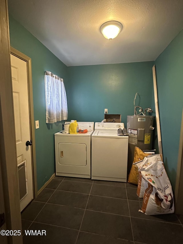 washroom featuring washing machine and clothes dryer, electric water heater, a textured ceiling, dark tile patterned flooring, and laundry area