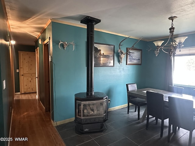 dining room featuring dark wood finished floors, a wood stove, crown molding, and baseboards