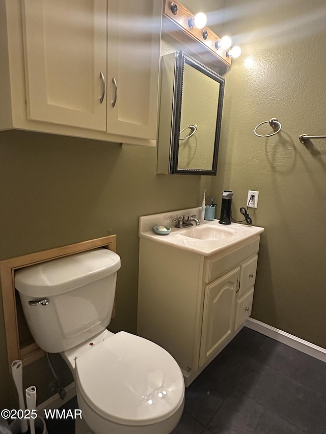 bathroom featuring toilet, baseboards, and vanity