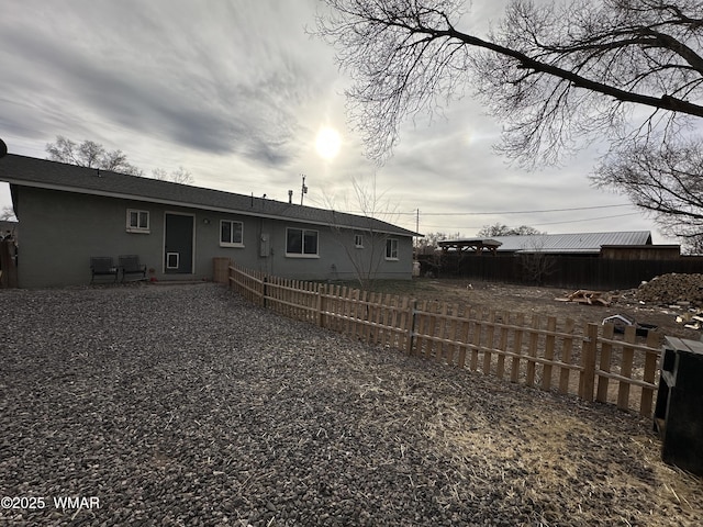 rear view of house featuring fence and stucco siding