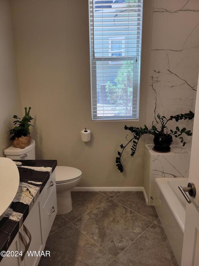 bathroom featuring a tub, baseboards, vanity, and toilet