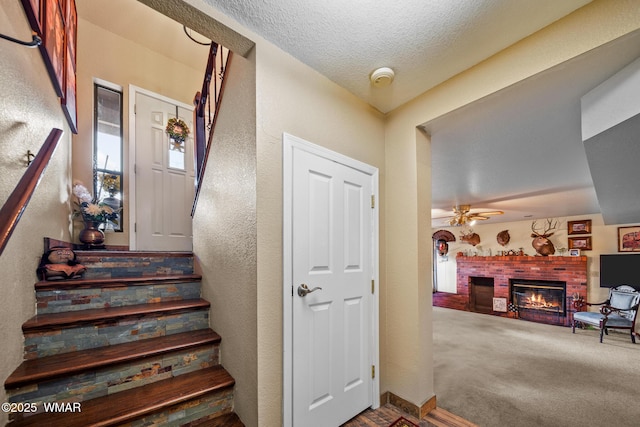 6711 Bandido Way, Show Low, AZ 85901 - stairway featuring a brick fireplace, a ceiling fan, a textured ceiling, and carpet