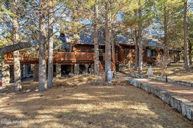 rear view of house featuring stairway, metal roof, log exterior, a deck, and stone siding