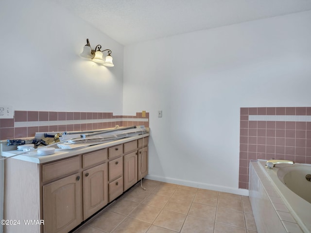 full bath featuring a textured ceiling, a relaxing tiled tub, baseboards, tile patterned floors, and double vanity