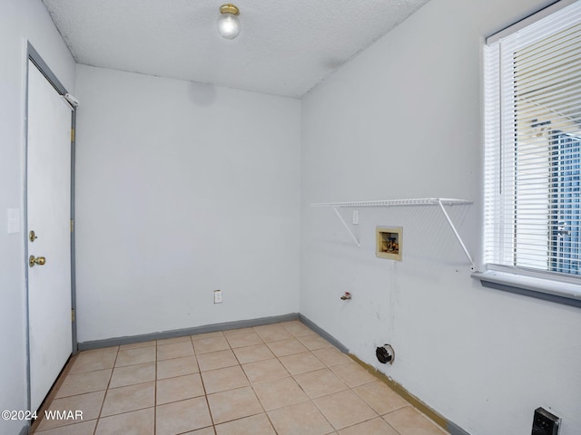 laundry area featuring laundry area, light tile patterned floors, baseboards, a textured ceiling, and washer hookup