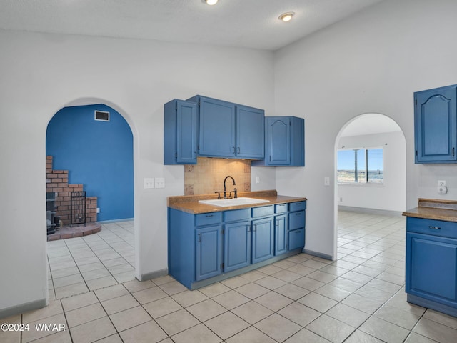 kitchen with blue cabinets, arched walkways, visible vents, and a sink