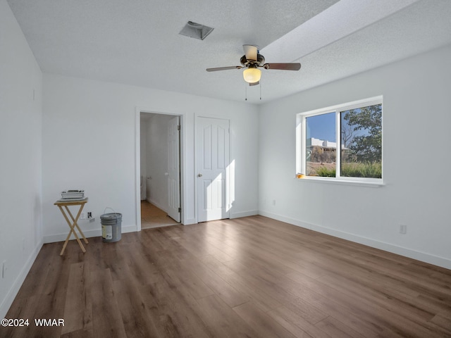 unfurnished bedroom with visible vents, a textured ceiling, baseboards, and wood finished floors