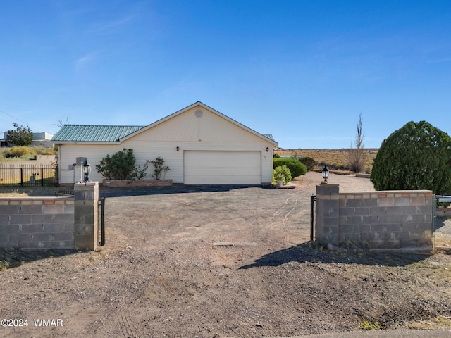 view of front of property featuring a garage, dirt driveway, fence, and metal roof