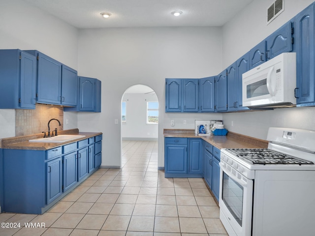 kitchen featuring arched walkways, blue cabinets, white appliances, a sink, and visible vents