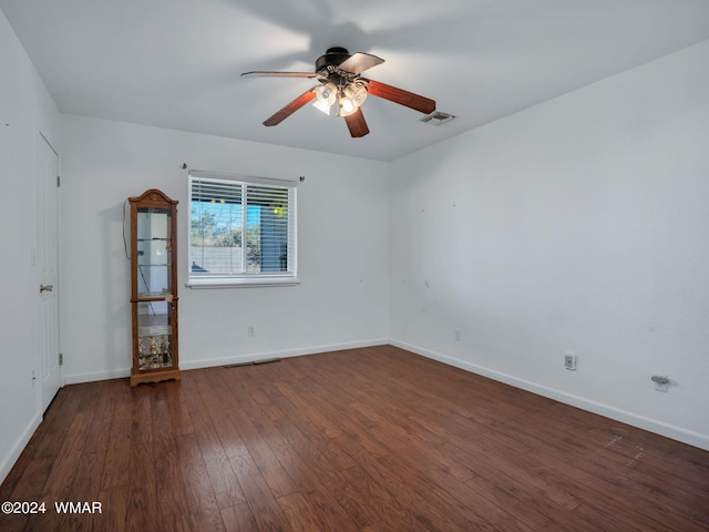 spare room featuring a ceiling fan, dark wood-style flooring, visible vents, and baseboards