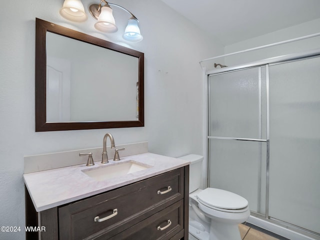 bathroom with toilet, a stall shower, and vanity