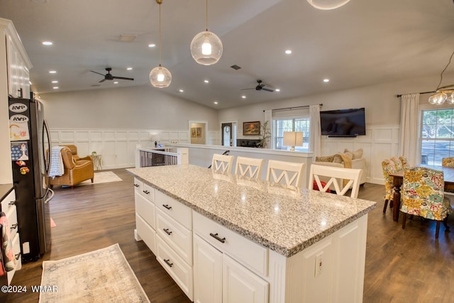 kitchen featuring white cabinets, open floor plan, freestanding refrigerator, a center island, and decorative light fixtures