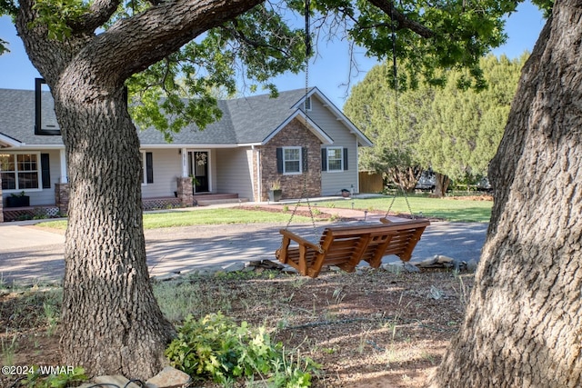 view of front of property with stone siding, roof with shingles, and a front yard