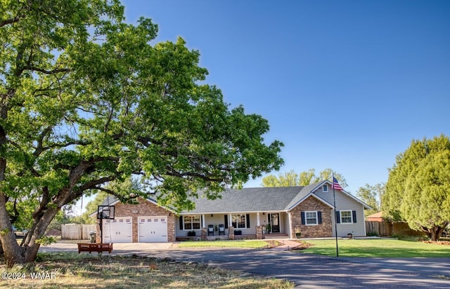 ranch-style house featuring a garage, concrete driveway, fence, and a front lawn