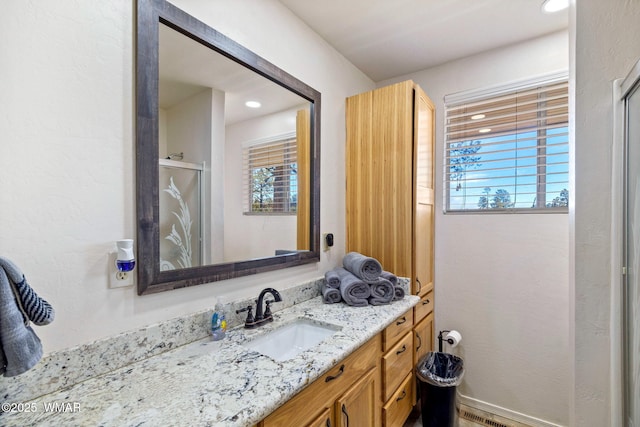 bathroom with a stall shower, vanity, and a healthy amount of sunlight