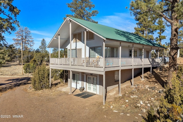 back of house with dirt driveway, metal roof, and french doors