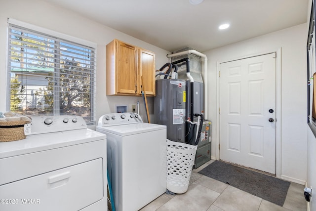 washroom with cabinet space, light tile patterned flooring, electric water heater, washer and dryer, and baseboards