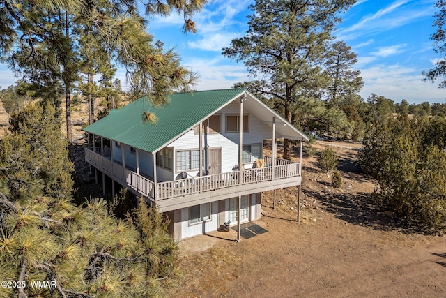 rear view of house featuring metal roof, a garage, and dirt driveway