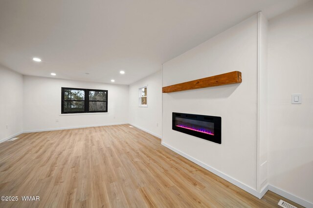 1259 S Penrod Dr, Pinetop, AZ 85935 - unfurnished living room featuring light wood-style flooring, a glass covered fireplace, and recessed lighting