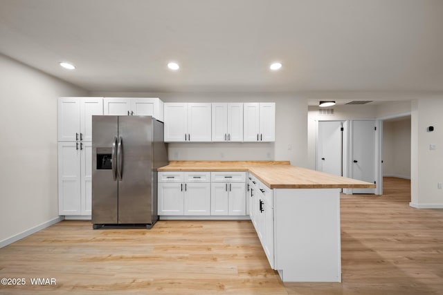 1259 S Penrod Dr, Pinetop, AZ 85935 - kitchen with stainless steel fridge, butcher block counters, a peninsula, light wood-style flooring, and white cabinets