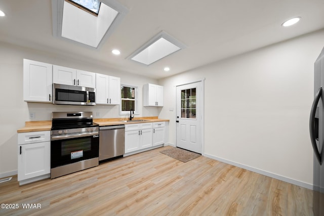 1259 S Penrod Dr, Pinetop, AZ 85935 - kitchen with appliances with stainless steel finishes, wood counters, a skylight, light wood finished floors, and white cabinets