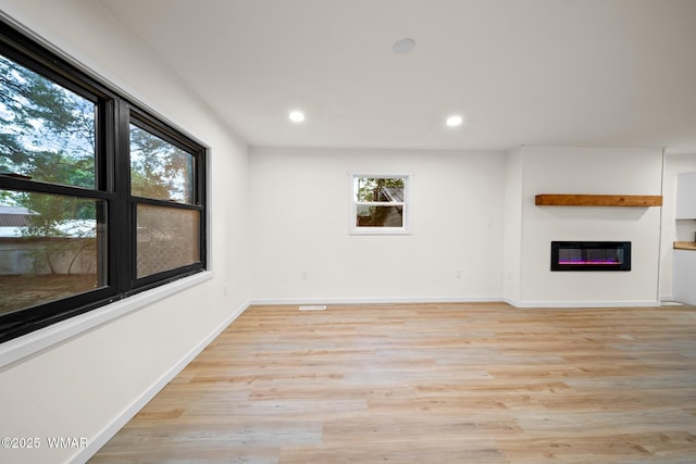 1259 S Penrod Dr, Pinetop, AZ 85935 - unfurnished living room featuring a glass covered fireplace, recessed lighting, and light wood-type flooring
