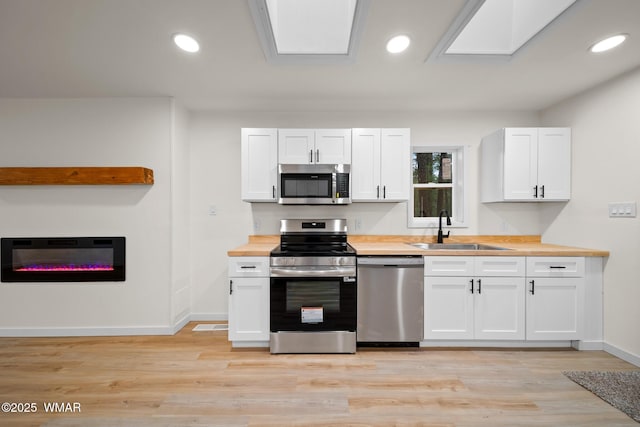 1259 S Penrod Dr, Pinetop, AZ 85935 - kitchen featuring appliances with stainless steel finishes, wood counters, white cabinetry, light wood finished floors, and recessed lighting