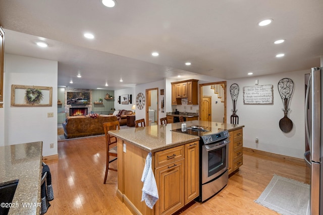 3530 Soaring Eagle Way, Pinetop, AZ 85935 - kitchen with appliances with stainless steel finishes, a fireplace, light wood-type flooring, light stone counters, and open floor plan