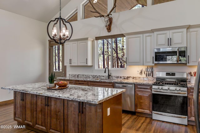 kitchen with stainless steel appliances, a chandelier, dark wood finished floors, a sink, and lofted ceiling
