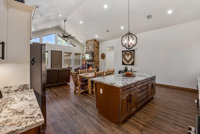 kitchen with a ceiling fan, a stone fireplace, open floor plan, dark wood finished floors, and recessed lighting