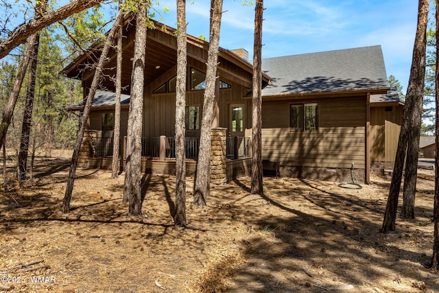 view of front of property with crawl space, roof with shingles, a porch, and board and batten siding