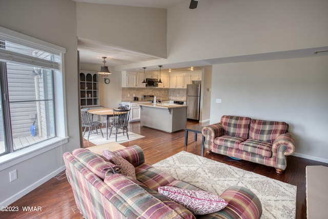 living area featuring visible vents, dark wood-style floors, baseboards, and high vaulted ceiling