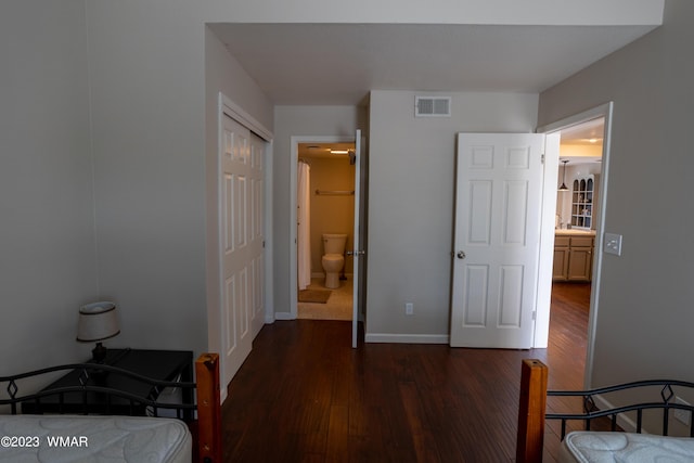 bedroom with visible vents, baseboards, dark wood-style floors, and ensuite bathroom