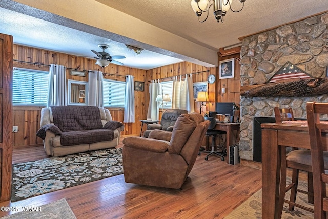 1888 Meadow St, Lakeside, AZ 85929 - living room with a textured ceiling, wood walls, beam ceiling, hardwood / wood-style flooring, and ceiling fan with notable chandelier
