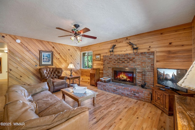 38684 State Route 373, Greer, AZ 85927 - living area featuring a brick fireplace, wooden walls, light wood-type flooring, ceiling fan, and a textured ceiling