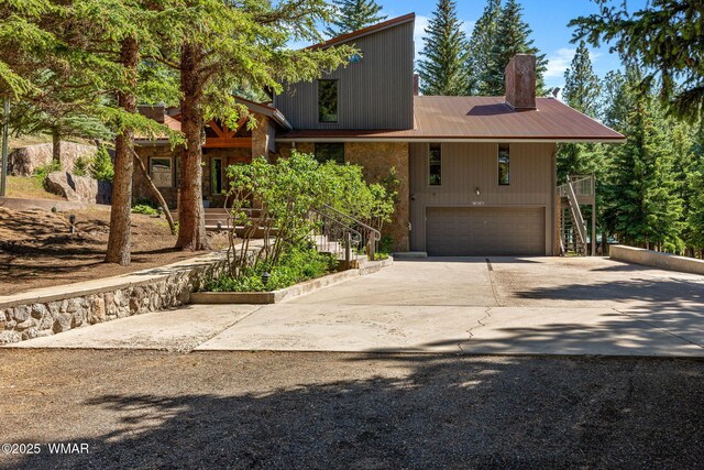 38684 State Route 373, Greer, AZ 85927 - mid-century modern home featuring stairs, concrete driveway, a garage, a chimney, and a metal roof