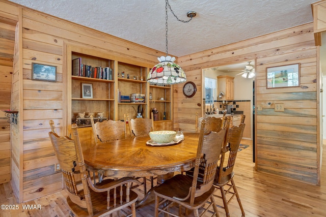 38684 State Route 373, Greer, AZ 85927 - dining area featuring a textured ceiling, wood walls, ceiling fan, and light wood finished floors