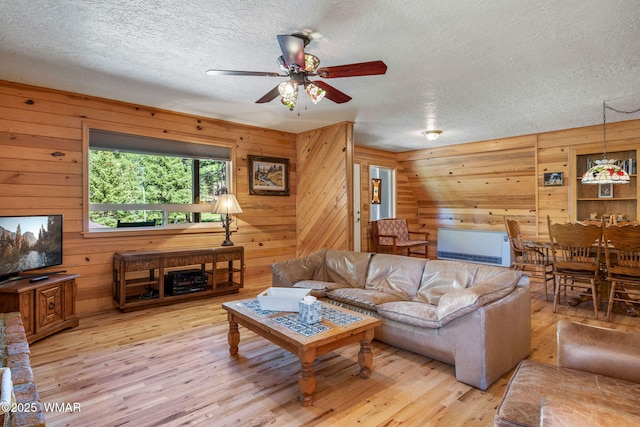 38684 State Route 373, Greer, AZ 85927 - living area featuring a ceiling fan, light wood-type flooring, a textured ceiling, and wooden walls