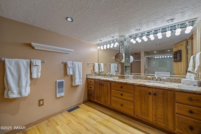 38684 State Route 373, Greer, AZ 85927 - bathroom with a textured ceiling, double vanity, a stall shower, wood finished floors, and heating unit